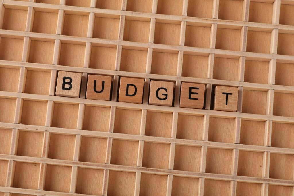 Wooden Scrabble tiles spelling 'budget' on a textured wooden grid, symbolizing financial planning.