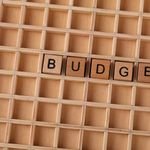 Wooden Scrabble tiles spelling 'budget' on a textured wooden grid, symbolizing financial planning.
